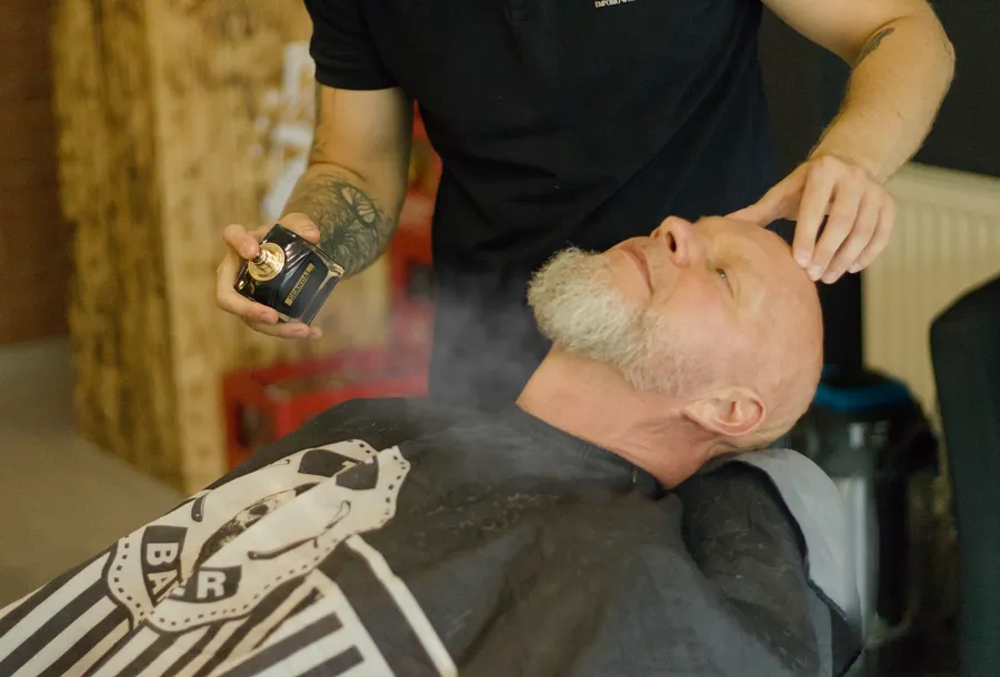 Barber psika klienta perfumami na koniec wizyty w Piglobarbershop w Koninie