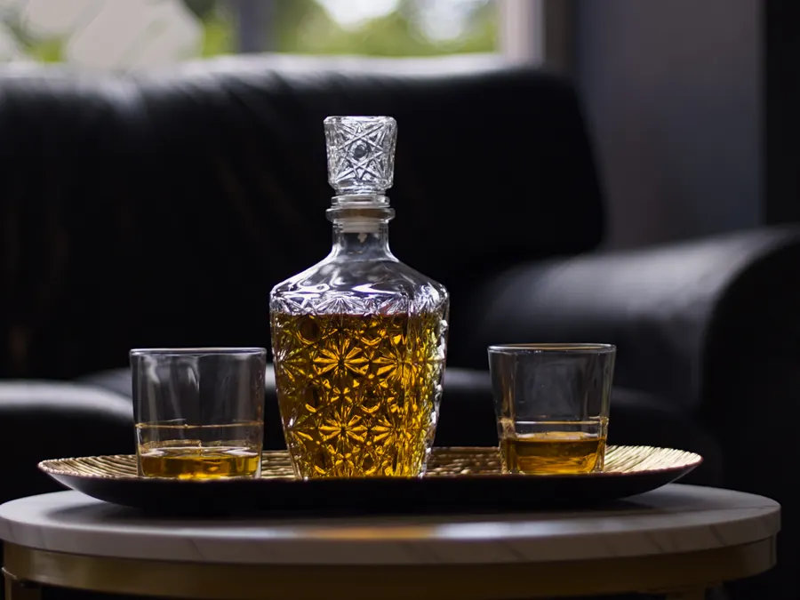 Karafka whisky ze szklankami w poczekalni Piglobarbershop w Koninie